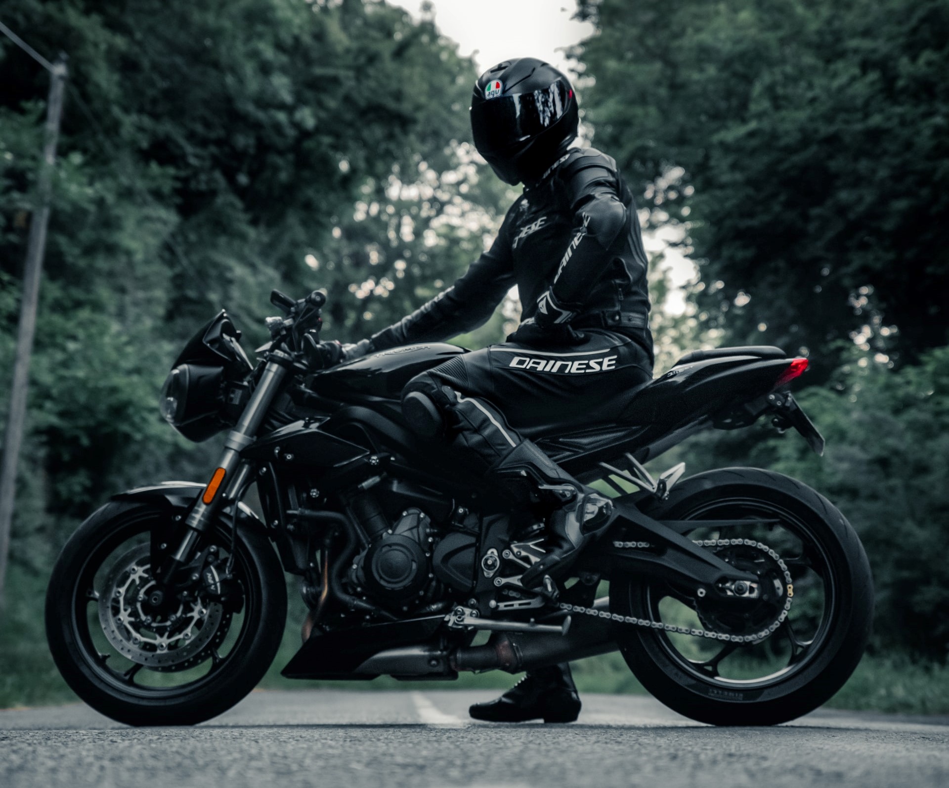 Motorkár sedí na motorke v čiernej kombinéze na motorku