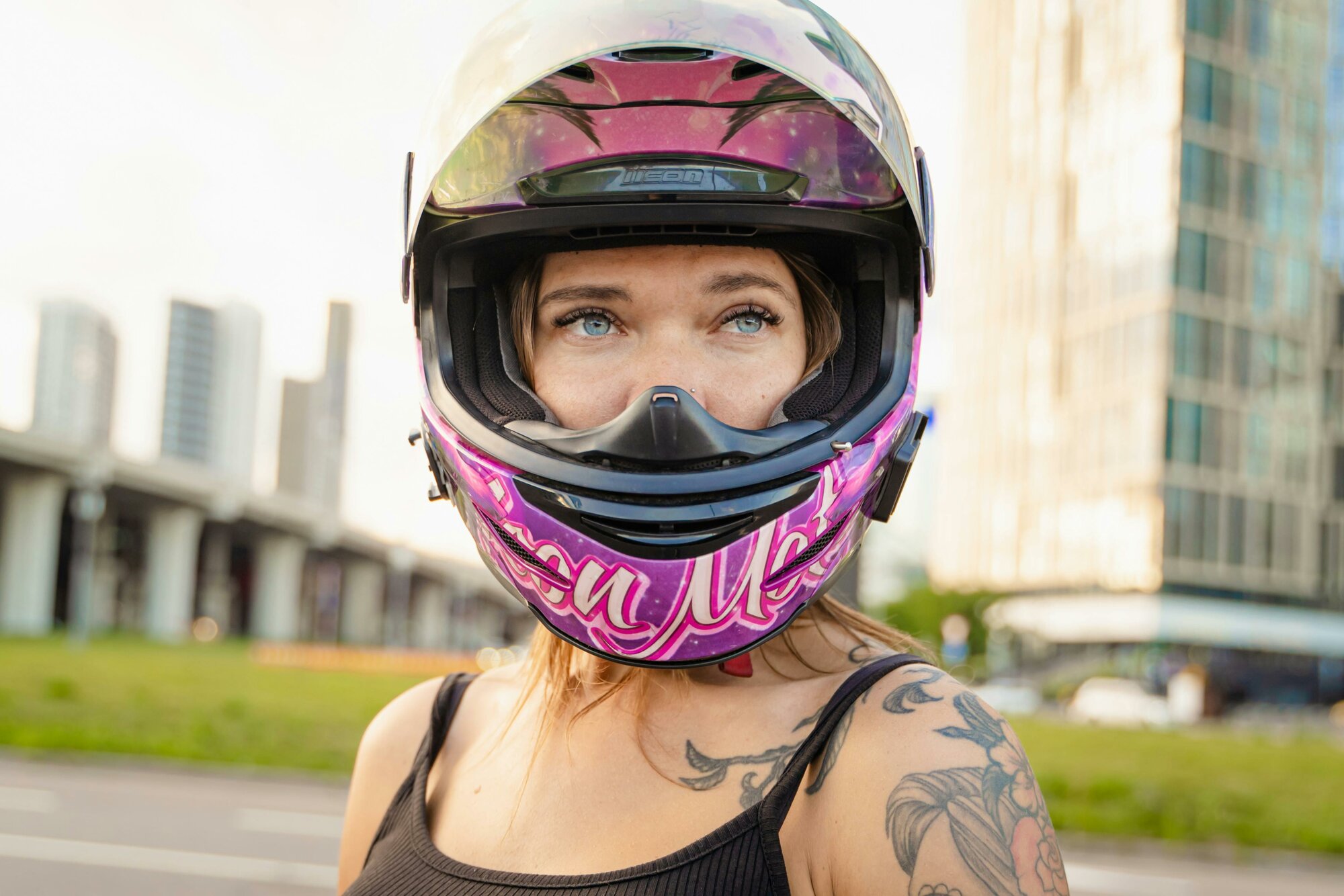 Žena má na hlave ružovú prilbu na motorku.