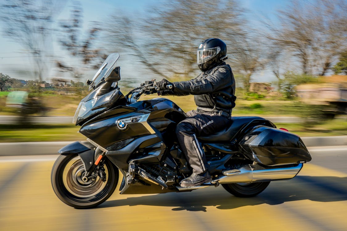 Motorkár v prilbe jazdí na BMW motorke na ceste